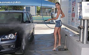 Dark-haired bombshell in a denim skirt pumps gas, shows pussy