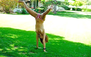 Sporty girl with attractive feet is doing cartwheels and stripping naked