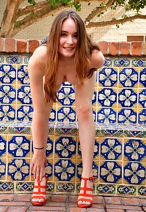 Long-legged redhead takes off her shoes and then poses totally naked